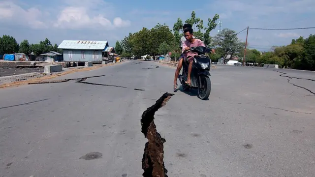 Um motociclista passa por uma rachadura na estrada após o terremoto na província de Nusa Tenggara Oriental, na Indonésia.