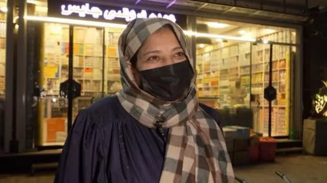 خانمی دچار بیماری دیابت و فشار خون است او با ماسک و چادر در جلو یک دواخانه ایستاده است.