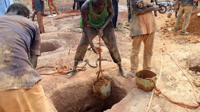 Gold miners empty containers of earth removed from a mining shaft in Koflatie, Mali, on October 28, 2014