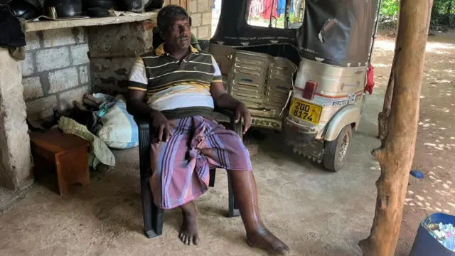 අනතුරට ලක්වූ ත්‍රිරෝද අසල සිටින ගීතිකාගේ සැමියා 