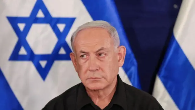 Umushikiranganji wa mbere wa Israel mw'ifoto ari imbere y'ibendera ry'igihugu ciwe  Benjamin Netanyahu pictured in front of an Israeli flag 