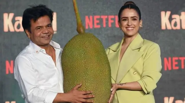 راجپال یاداو و بازیگر زنی که در فلم کاتال: معمای جک‌فروت با هم بازی کرده اند. این دو یک میوه جک‌فروت بزرگ را در دست گرفته اند. 