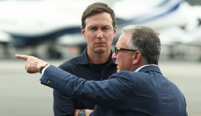 İki erkek havalimanının pistinde konuşuyor, biri eliyle bir yeri işaret ediyor