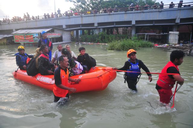 Relawan gabungan mengevakuasi warga korban banjir dengan perahu karet di Karanganyar, Demak, Jawa Tengah, Minggu (17/3/2024).