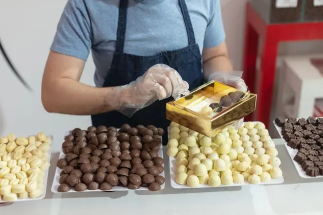çikolata standından görüntü, bir satıcı kutu dolduruyor.