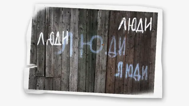 Надпись «Люди» белой краской на деревянных воротах дома