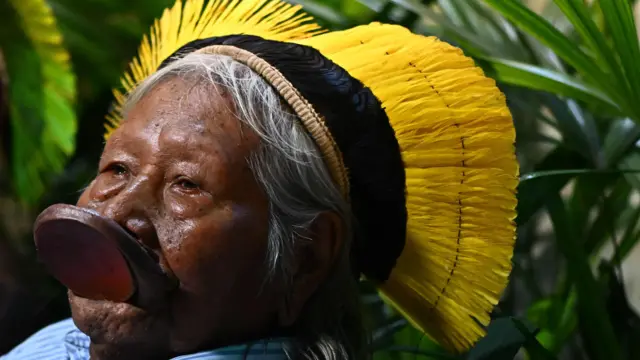 Imagem de perfil do cacique Raoni; ele aparece sério, observando algo 