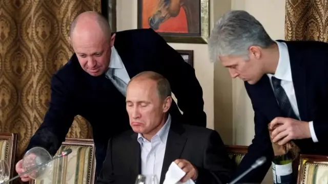 Yevgeny Prigozhin (kushoto) pichani akimhudumia Vladimir Putin (katikati) wakati wa chakula cha jioni mwaka 2011