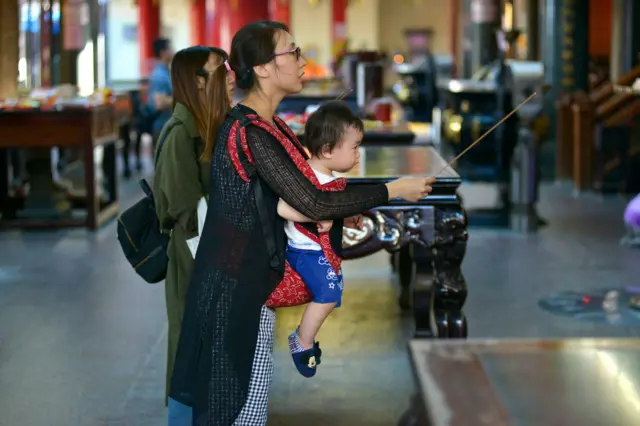 图为一对母子在台湾宫庙参拜。