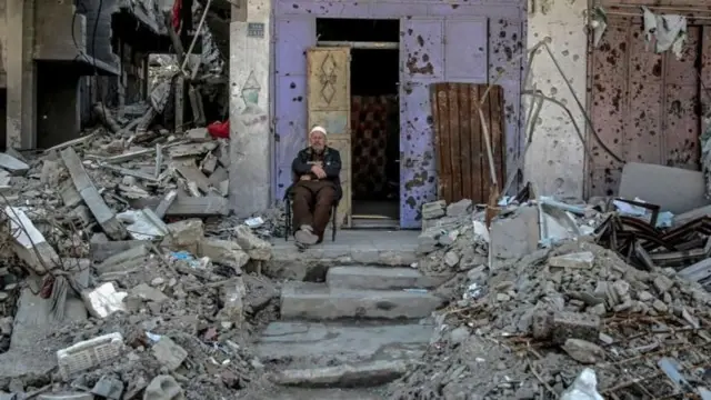 Un homme assis face à des décombres