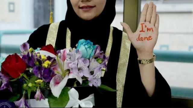 یک دانشجوی افغان با لباس فراغت و دسته گل در ایران