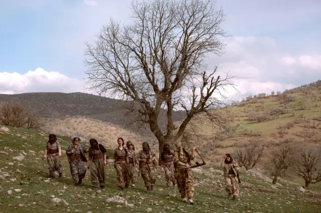 A group of female fighters walk down the hill after a military exercise