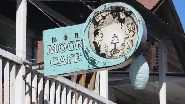 Imagemcomo criar aposta na bet 365uma placa onde se lê 'Moon Café', seguidocomo criar aposta na bet 365um desenhocomo criar aposta na bet 365um homem e uma mulhercomo criar aposta na bet 365uma mesa conversando 