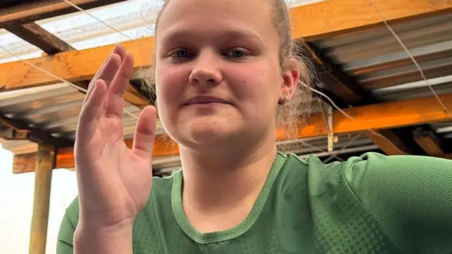 Meri Prinsloo fait un geste à la caméra en levant le bras droit avant un bras de fer.