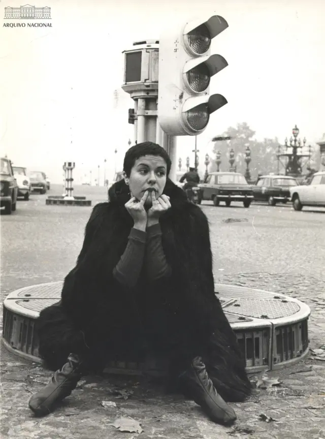 Elis sentada em rotatória com farol