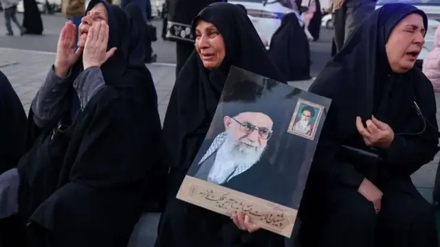 زنان سیاهپوش با چادرهای مشکی در حالی که تصویر علی خامنهای را در دست دارند، سوگواری میکنند.