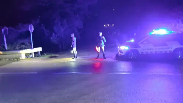 救急隊員2人が道路の真ん中に立っている。近くにはライトをつけた救急車両が止まっている