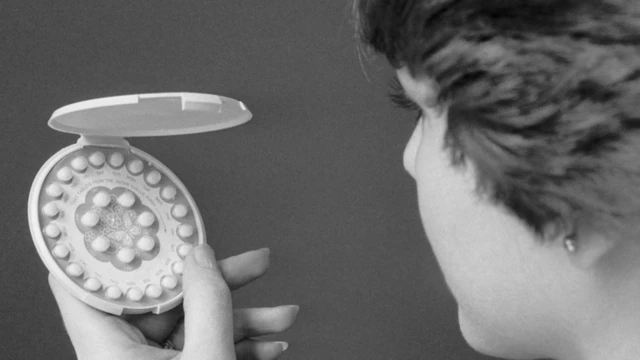 A woman holding early birth control pills