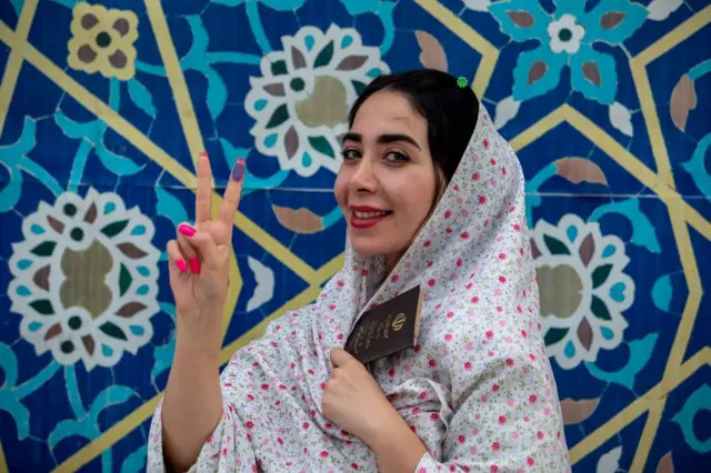 سيدة إيرانية ترفع إصبعيها بعلامة النصر بعد الإدلاء بصوتها في الانتخابات الرئاسية الإيرانية لعام 2024.