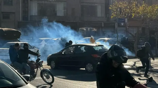 Suzavac koji se širi ulicom na kojoj su ljudi na motorima okruženi automobilima