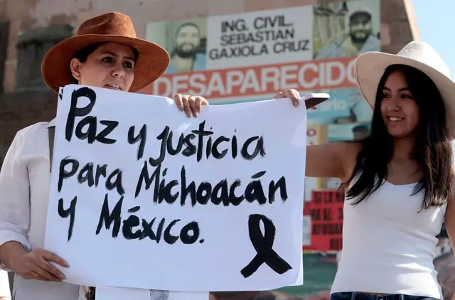 Dos mujeres sostienen una pancarta que dice "Paz y justicia para Michoacán y México" durante la marcha "Por la Paz" organizada por la Generación Z contra el gobierno de la presidenta mexicana Claudia Sheinbaum en Guadalajara, Jalisco, México, el 15 de noviembre de 2025. Miles de personas marcharon por las calles de la Ciudad de México el sábado para protestar contra la violencia de las drogas y las políticas de seguridad del gobierno de la presidenta Claudia Sheinbaum. (Foto de ULISES RUIZ / AFP) (Foto de ULISES RUIZ/AFP vía Getty Images)
