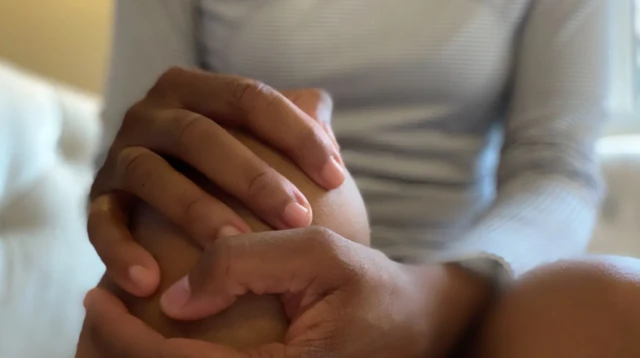 Quelqu'un tient avec ses deux mains le genou d'une autre personne 