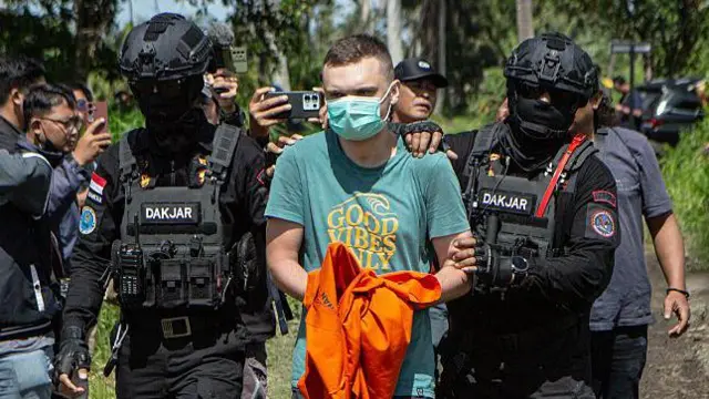 Tersangka warga negara Rusia S.T. (C), 34 tahun, yang dituduh mengoperasikan laboratorium yang memproduksi narkoba sintetis mephedrone, dikawal polisi ke rumah yang digunakan untuk memproduksi narkoba selama rekonstruksi TKP saat pihak berwenang mencari tersangka asing lainnya di Gianyar, pulau wisata Bali, Indonesia pada 7 Maret 2026. 