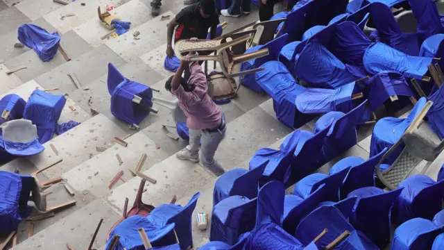 印度加尔各答盐湖体育场内，一名男子在水泥看台上摔毁塑胶座椅（13/12/2025）