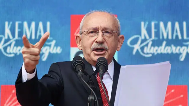 Kılıçdaroğlu kürsüden konuşuyor. Elinde kağıtlar, önünde mikrofon var.
