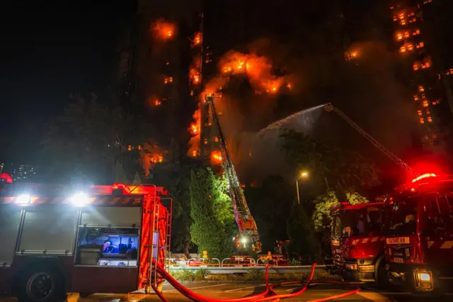消防表示,目前有两、三座大楼仍严峻,现场温度高。图中有两架消防车停泊,架起钢梯向大厦射水。
