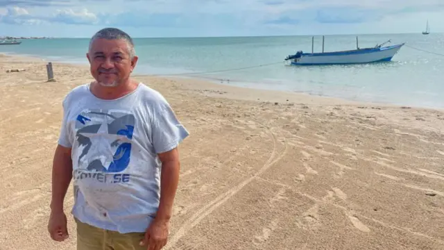 Pescador com o mar e barco de pesca ao fundo