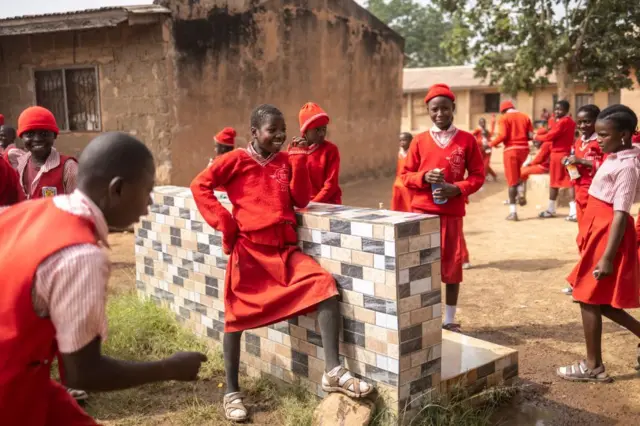 Une jeune fille se tient près du distributeur d'eau dans la cour de récréation du lycée baptiste de Sion à Jos, le 27 février 2025. 