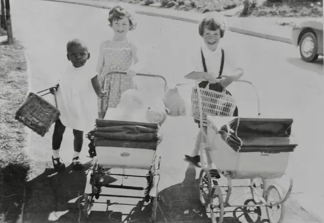 Ijeoma de unos 4 años con dos niñas que llevan coches de muñecas