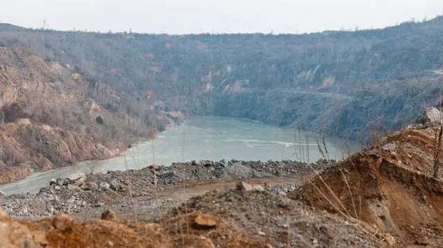 Заваллівський графітовий кар'єр у Кіровоградській області. Бурого кольору земля, озеро, схили, порослі чагарниками.