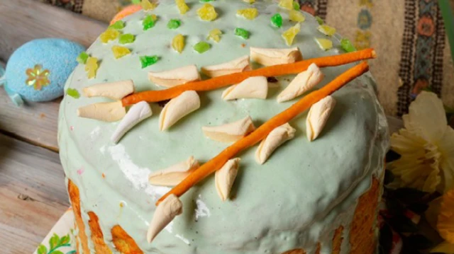 Гілочки "верби", виготовлені з кондитерських виробів, лежать на верхівці спеченої паски. 