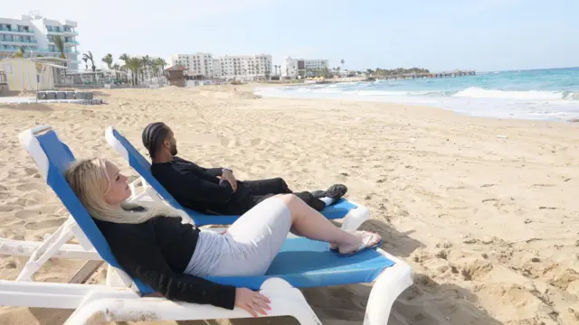 Swiss couple Alexandra and Jehiel on lounge chairs facing an empty beach