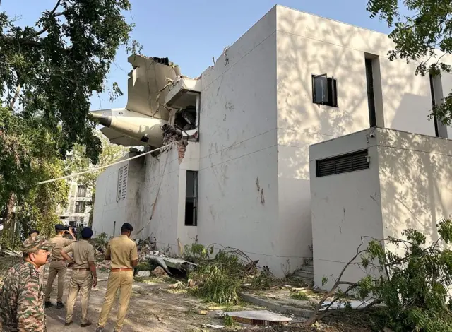 Bagian pesawat berada di antara bangunan di Ahmedabad, India, Kamis (12/06).