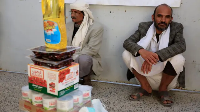 رجلان يجلسان على الأرض خلف منتجات غذائية