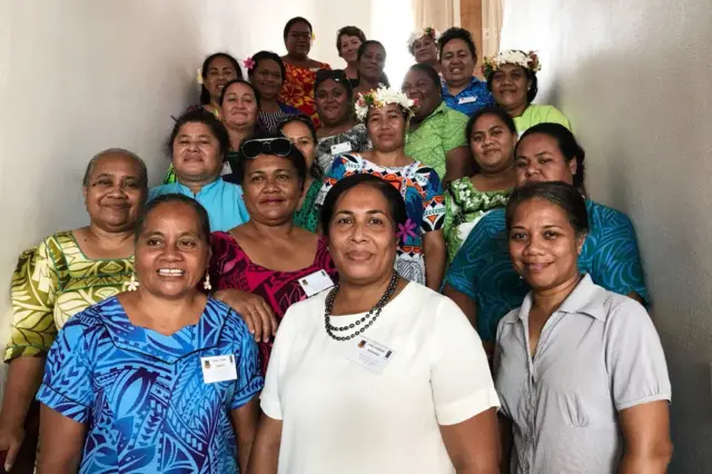 Le Dr Boreham pose entouré de 20 femmes, toutes souriantes, certaines en robe traditionnelle avec des fleurs dans les cheveux.