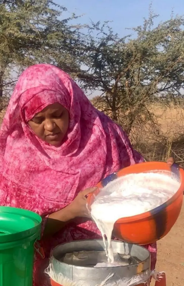 Madame Wouro Habsatou verse du lait de chamelle dans un réservoir.