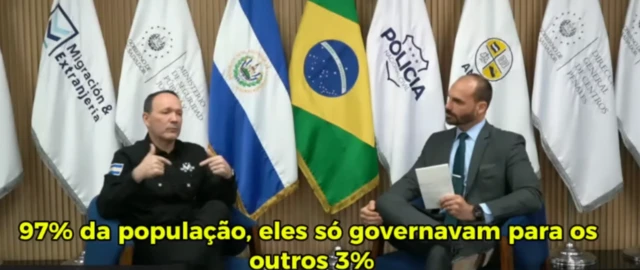 O ministro da segurança pública de El Salvador, Gustavo Villatoro, e o deputado federal Eduardo Bolsonaro, em entrevista publicada no Youtube do deputado. Na imagem aparecem bandeiras dos dos países ao fundo.