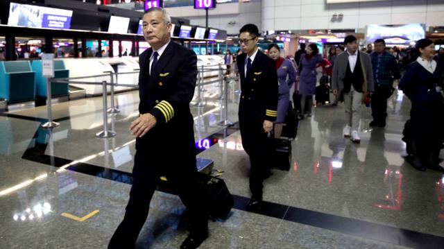 台湾桃园机场一队华航机组在机长带领下通过值机柜台（台湾中央社图片8/2/2019）