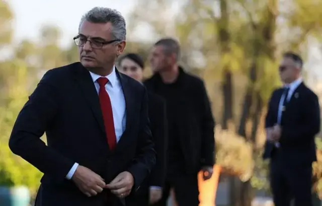 مردی در یک مراسم مذهبی در حال بستن دکمههای کتش