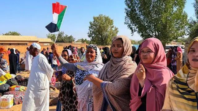 Une femme tient le drapeau soudanais alors que les personnes déplacées par la guerre en cours au Soudan retournent à Wad Madani dans l'état de Jazira, le 6 février 2025, après que la ville ait été reprise par l'armée soudanaise.
