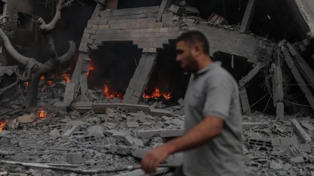 Un hombre pasa delante de un edificio en llamas en la ciudad de Gaza este 9 de octubre.