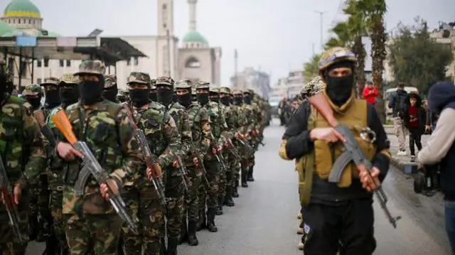 HŞT'nin askeri eğitiminde sıraya dizilmiş yüzleri maskeli elleri silahlı savaşçılar