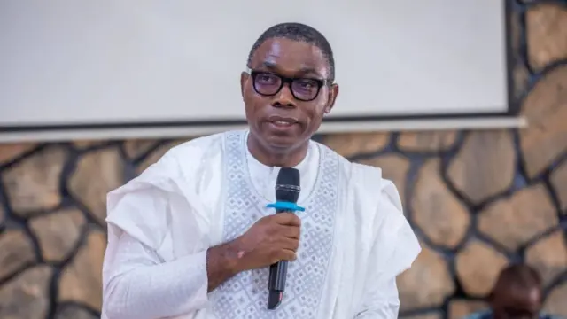 Adewole Adebayo wear white outfit and e hold mic