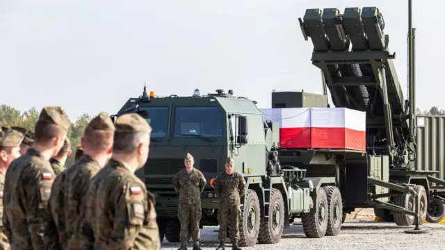 Польські військові стоять біля пускової установки системи протиповітряної оборони Patriot, встановленої на військовій базі. На техніці розміщено польський прапор, а на задньому плані видно елементи ракетного комплексу.