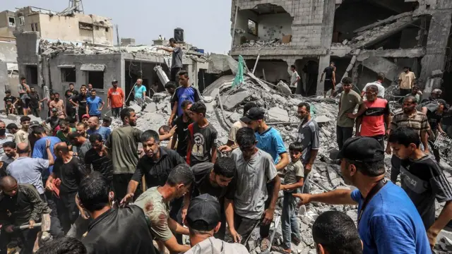 يقوم السكان وفرق الدفاع المدني بعمليات بحث وإنقاذ بين أنقاض المباني المدمرة في أعقاب الهجوم الإسرائيلي على مخيم خان يونس للاجئين في خان يونس، غزة، في 1 يوليو/تموز 2025.
