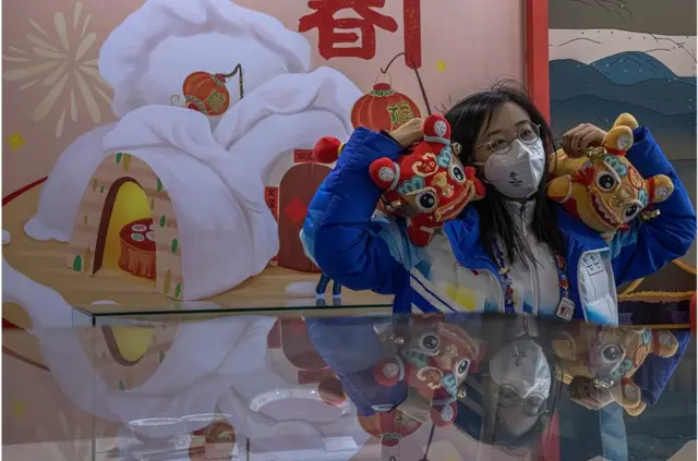 北京2022年冬奥会定于2月4日开幕。奥运志愿者在奥运主媒体中心与老虎玩具合影，该中心是新冠疫情下奥运"闭环"的一部分。